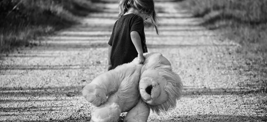 Schwarz  Weiß Foto von einem Kind mit Teddybär
